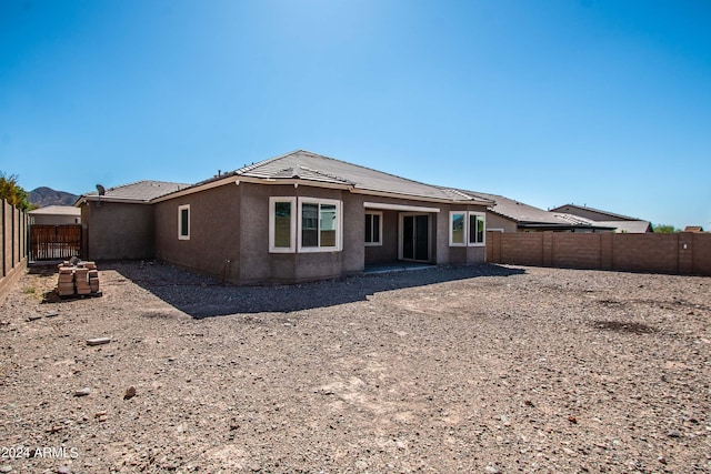 back of property featuring a fenced backyard, a tile roof, and stucco siding