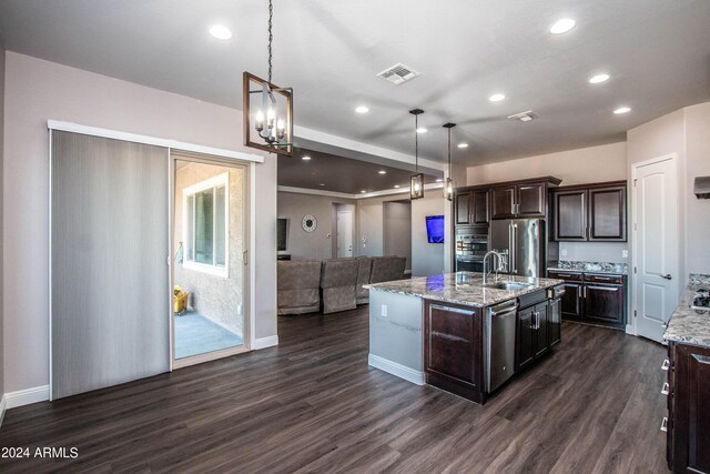 kitchen with appliances with stainless steel finishes, dark hardwood / wood-style flooring, pendant lighting, and an island with sink