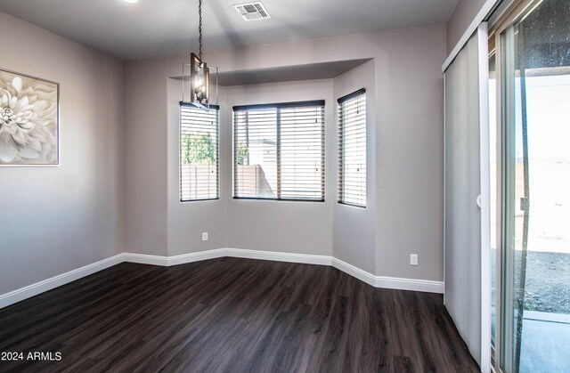 empty room featuring a notable chandelier and dark wood-type flooring