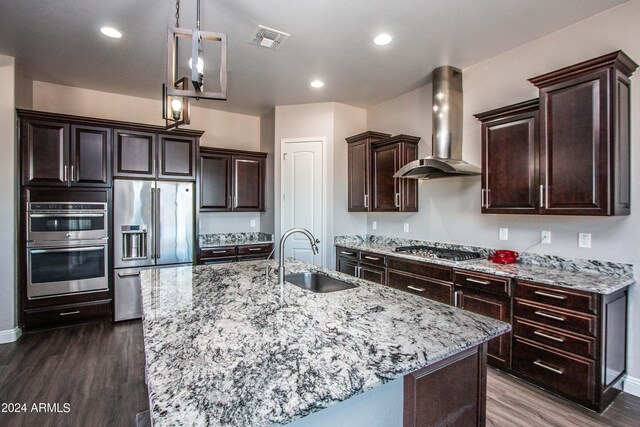 kitchen featuring dark brown cabinetry, sink, wall chimney exhaust hood, stainless steel appliances, and dark hardwood / wood-style flooring