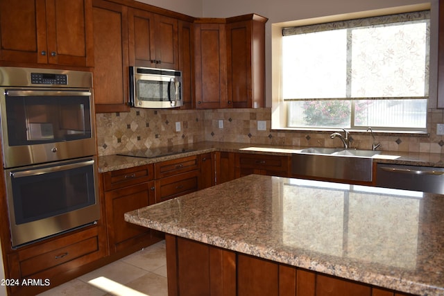 kitchen with stainless steel appliances, light tile patterned flooring, a sink, and tasteful backsplash