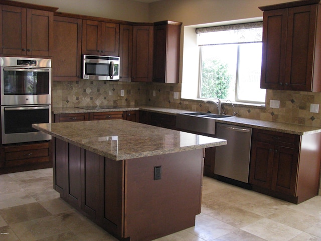 kitchen featuring appliances with stainless steel finishes, backsplash, a sink, and a center island