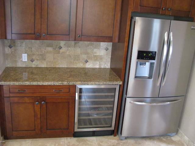 kitchen featuring stainless steel refrigerator with ice dispenser, light stone countertops, beverage cooler, and tasteful backsplash