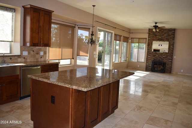 kitchen featuring stone counters, a kitchen island, open floor plan, stainless steel dishwasher, and backsplash