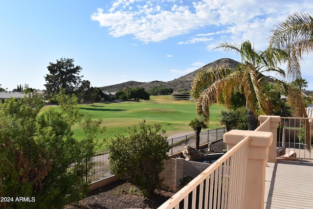 view of home's community featuring fence, a mountain view, golf course view, and a lawn