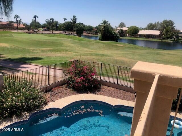 view of pool with view of golf course, a lawn, a water view, and fence