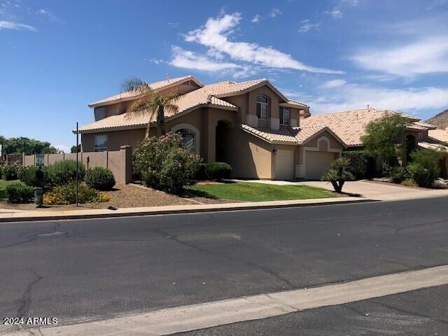 mediterranean / spanish home featuring a garage, fence, a tile roof, driveway, and stucco siding