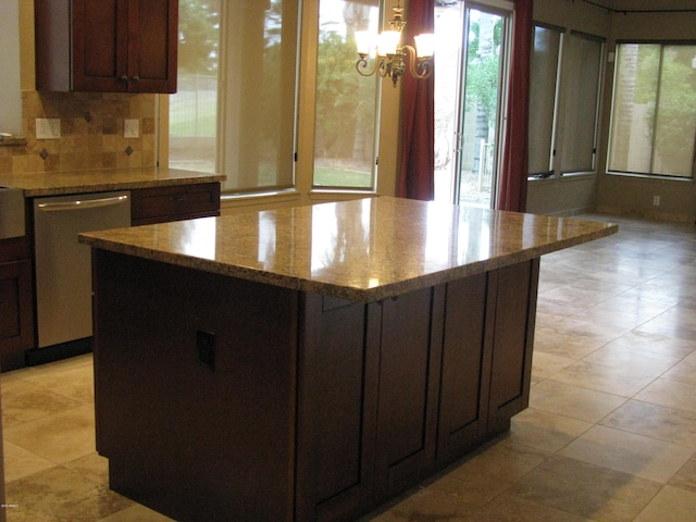 kitchen with backsplash, a center island, a healthy amount of sunlight, and stainless steel dishwasher