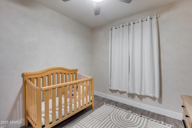 12211 W Hide Trl, Peoria, AZ 85383 - bedroom featuring wood finished floors, a crib, and ceiling fan