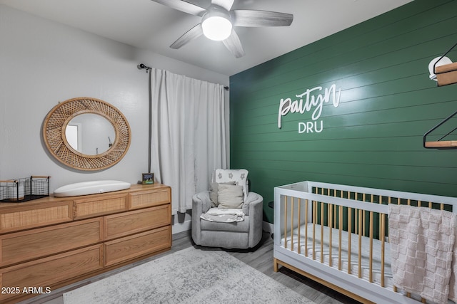 12211 W Hide Trl, Peoria, AZ 85383 - bedroom featuring wood finished floors, a nursery area, wood walls, and a ceiling fan