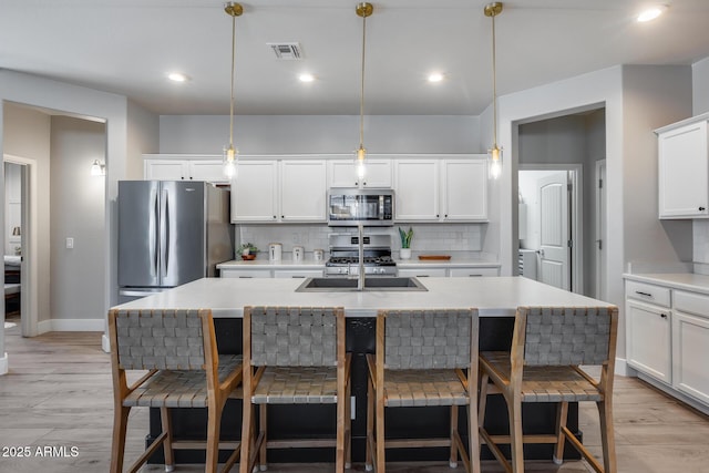 12211 W Hide Trl, Peoria, AZ 85383 - kitchen with appliances with stainless steel finishes, decorative backsplash, an island with sink, a kitchen breakfast bar, and white cabinets