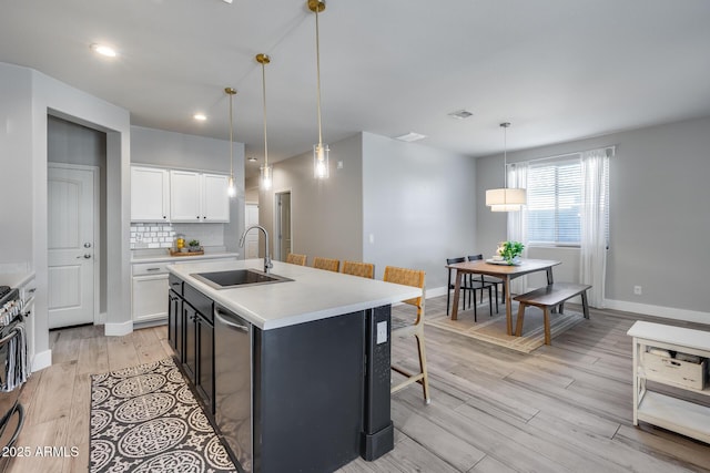 12211 W Hide Trl, Peoria, AZ 85383 - kitchen featuring light wood finished floors, white cabinets, light countertops, an island with sink, and decorative light fixtures