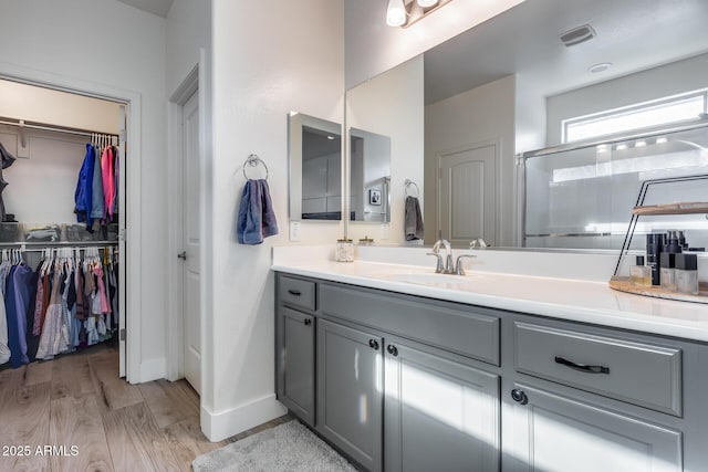 12211 W Hide Trl, Peoria, AZ 85383 - bathroom featuring vanity, a walk in closet, wood finished floors, and a stall shower