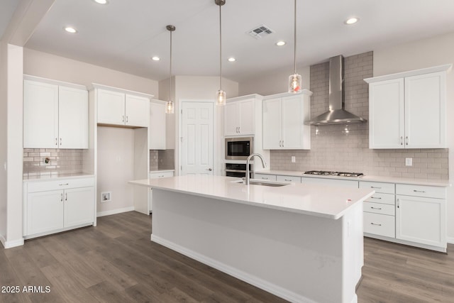 kitchen with white cabinetry, wall chimney range hood, and hanging light fixtures