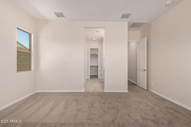 unfurnished bedroom with light colored carpet and a spacious closet