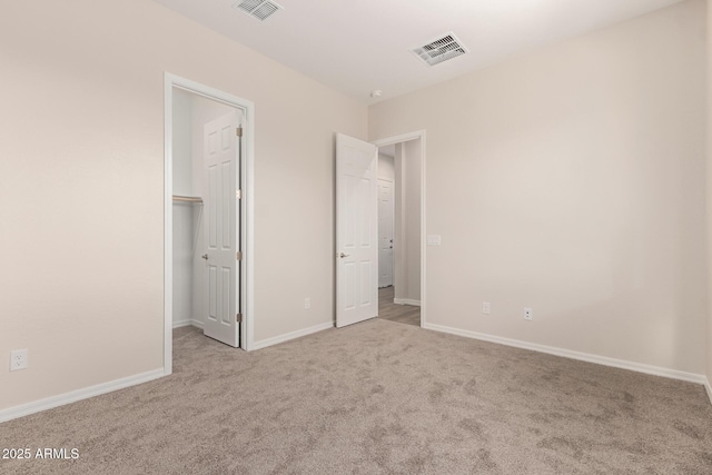 unfurnished bedroom featuring a walk in closet, light carpet, and a closet