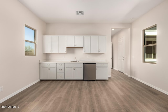 kitchen featuring white cabinetry, sink, dishwasher, and light wood-type flooring