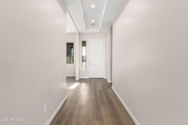 hallway featuring dark hardwood / wood-style flooring and a tray ceiling