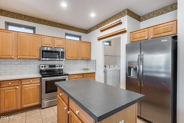 kitchen with appliances with stainless steel finishes, backsplash, light tile patterned floors, washing machine and clothes dryer, and a kitchen island