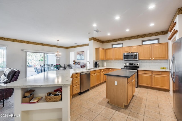 kitchen with decorative light fixtures, stainless steel appliances, a kitchen island, and sink