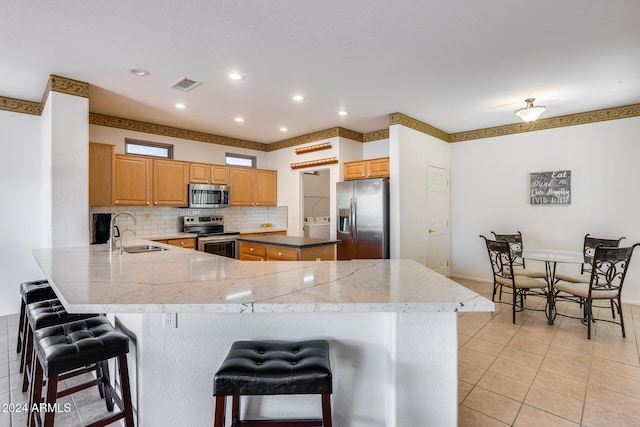 kitchen with a kitchen breakfast bar, kitchen peninsula, sink, and appliances with stainless steel finishes