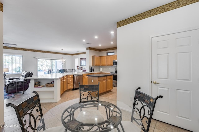 kitchen with kitchen peninsula, decorative backsplash, stainless steel appliances, decorative light fixtures, and a center island