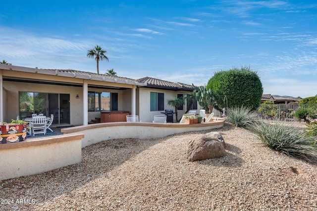 rear view of house featuring a patio and a hot tub