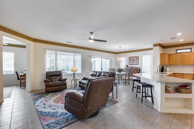 living room with sink, light tile patterned floors, a healthy amount of sunlight, and ceiling fan with notable chandelier