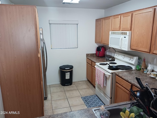 kitchen featuring light tile patterned flooring and white appliances