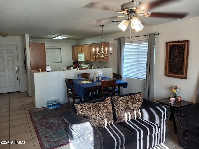 tiled dining space with ceiling fan with notable chandelier