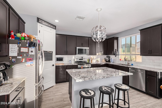 kitchen featuring pendant lighting, sink, dark brown cabinets, a kitchen island, and stainless steel appliances