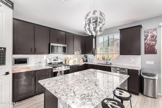 kitchen featuring decorative light fixtures, a kitchen island, sink, and appliances with stainless steel finishes