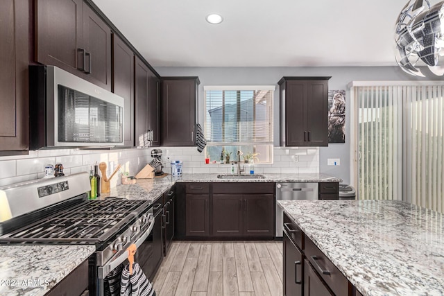 kitchen featuring light stone counters, stainless steel appliances, light hardwood / wood-style flooring, and sink