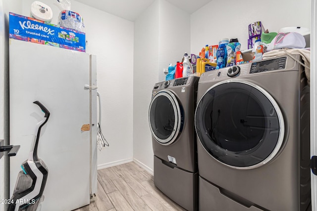 laundry area with light hardwood / wood-style floors and washing machine and clothes dryer