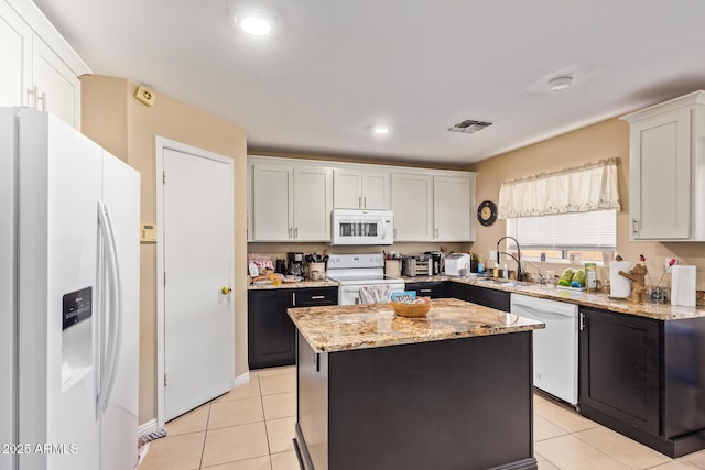 12426 W Surrey Ave, El Mirage, AZ 85335 - kitchen with light tile patterned floors, white appliances, white cabinets, visible vents, and a sink