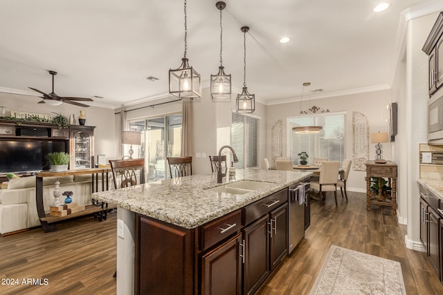 kitchen with a center island with sink, ornamental molding, dark hardwood / wood-style floors, decorative light fixtures, and sink