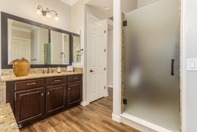 bathroom featuring vanity, ornamental molding, wood-type flooring, and walk in shower