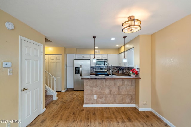 kitchen featuring kitchen peninsula, hanging light fixtures, light hardwood / wood-style floors, white cabinetry, and stainless steel appliances