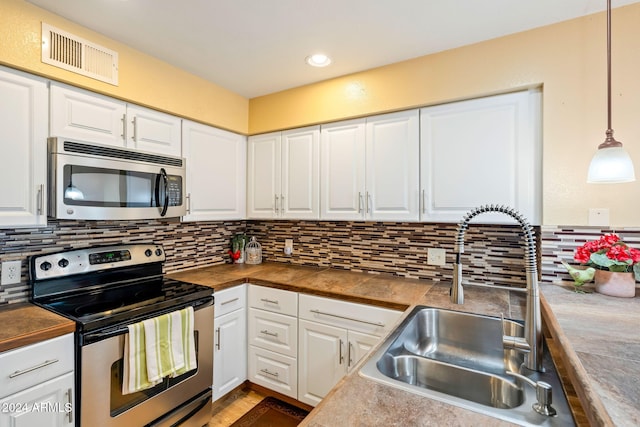 kitchen with butcher block countertops, white cabinetry, hanging light fixtures, and appliances with stainless steel finishes