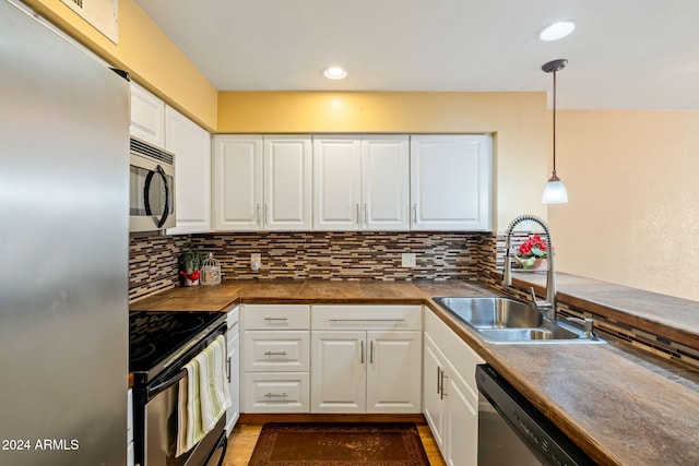 kitchen with decorative light fixtures, white cabinetry, sink, and appliances with stainless steel finishes