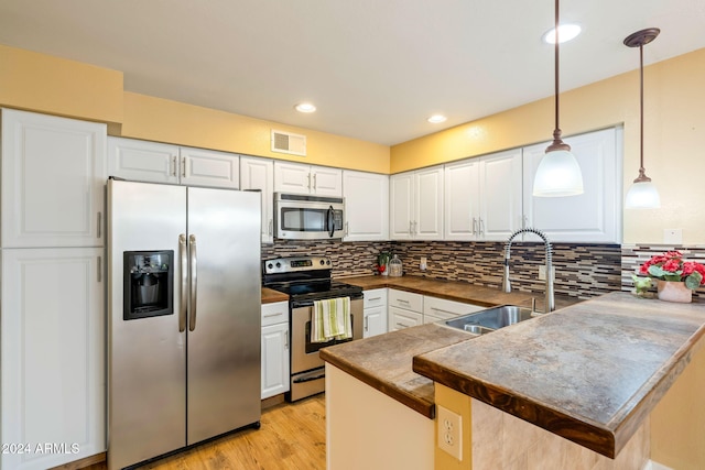 kitchen with kitchen peninsula, stainless steel appliances, white cabinets, and sink