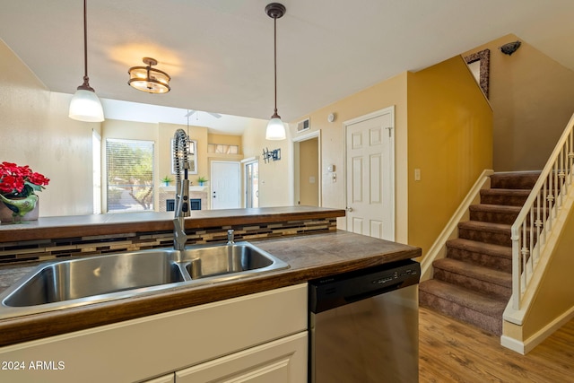 kitchen featuring pendant lighting, light hardwood / wood-style flooring, stainless steel dishwasher, and white cabinetry