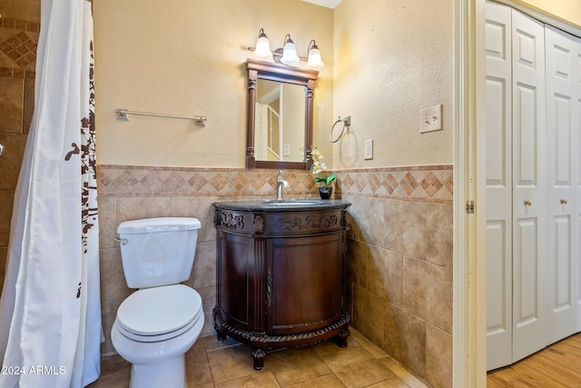 bathroom featuring vanity, toilet, and tile walls