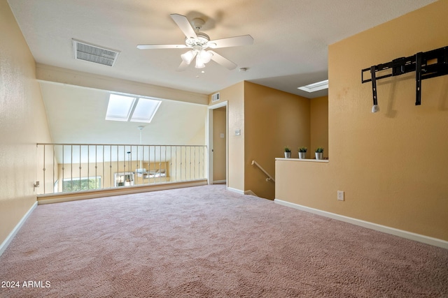 spare room with a skylight, ceiling fan, and carpet