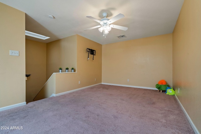 carpeted spare room featuring ceiling fan and a skylight