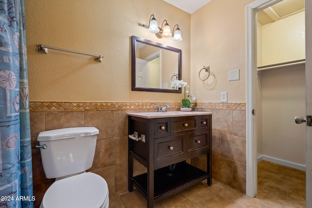 bathroom with tile patterned floors, vanity, toilet, and tile walls