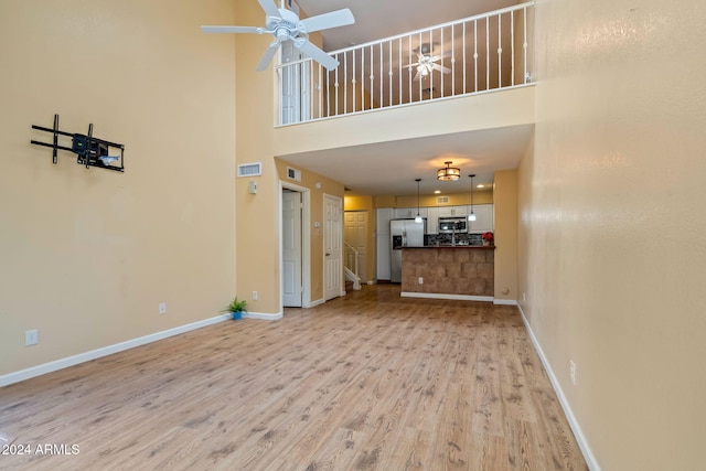 unfurnished living room featuring light hardwood / wood-style flooring and a high ceiling