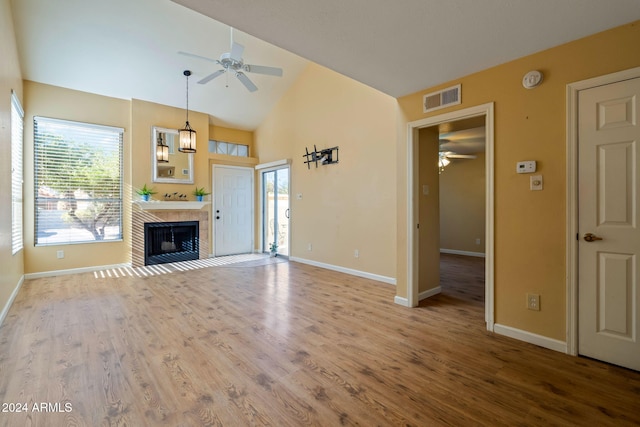 unfurnished living room featuring light wood-type flooring, high vaulted ceiling, ceiling fan, and a tiled fireplace