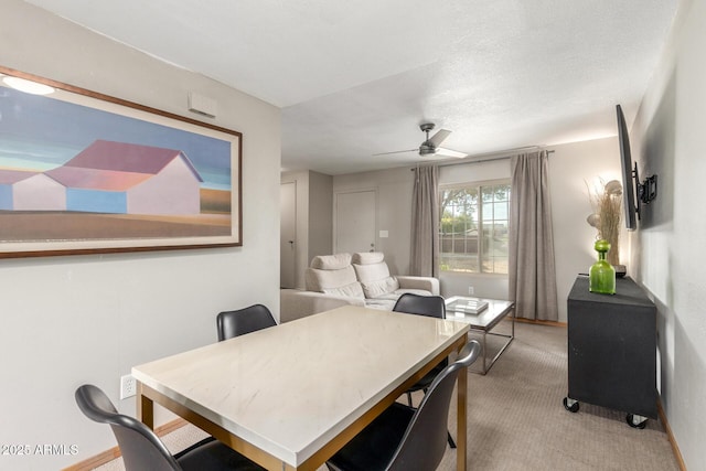 dining space with ceiling fan, light carpet, and a textured ceiling