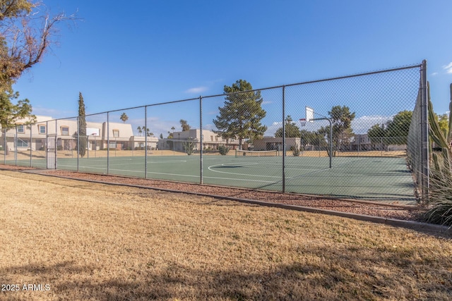 view of tennis court featuring basketball court and a lawn